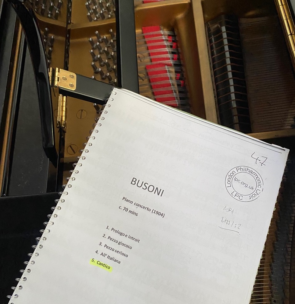 Image shows a score for Busoni's Piano Concerto resting on top of a black grand piano