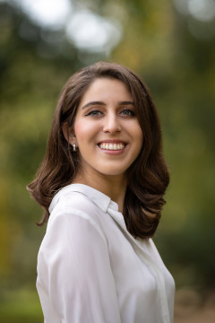 Image shows a photograph of a young woman with brown hair smiling